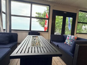 A room with a table, two sofas, and large windows with a view of trees and a flag.