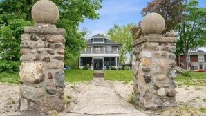 A pathway leading to a stone-structured entrance with a house in the background.