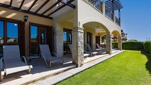 Una casa moderna con un porche cubierto, pilares de piedra y un césped bien cuidado.