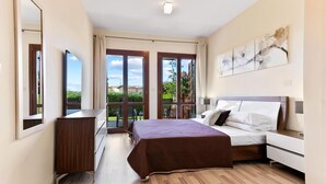 Un dormitorio con cama, cómoda, mesita de noche, espejo y ventana con vistas a la vegetación.