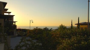 Vista costera con atardecer, edificios y un farol.
