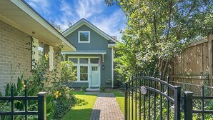 A residential property with a brick exterior, a front yard with a pathway, and a wooden fence. - Charming cottage! Central to beach & downtown (Mount Pleasant)