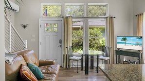 A living room with a leather couch, a glass-top coffee table, and a television on a stand. - Charming cottage! Central to beach & downtown (Mount Pleasant)