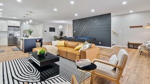 A modern living room with a sofa, coffee table, and a pool table.