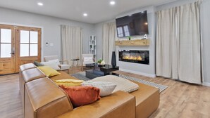 A modern living room with a leather sofa, a fireplace, and a television mounted on the wall.
