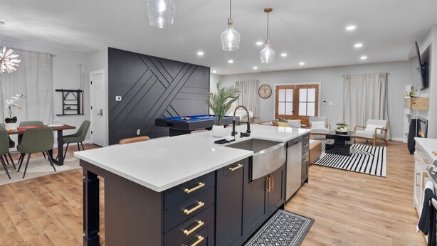 A modern kitchen with a central island, dark cabinetry, and pendant lighting.