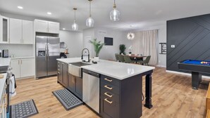 A modern kitchen with a central island, stainless steel appliances, and pendant lighting.