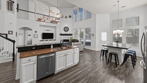 A spacious kitchen with a central island, white cabinetry, and a dark wood floor. - Keller’s Crown - Huge House Near Stadiums - Hot Tub & Pool Table (Keller)