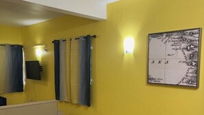 Ein Zimmer mit gelben Wänden, einem schwarzen Tisch mit vier gelben Stühlen, einer weißen Theke und einer Karte an der Wand.