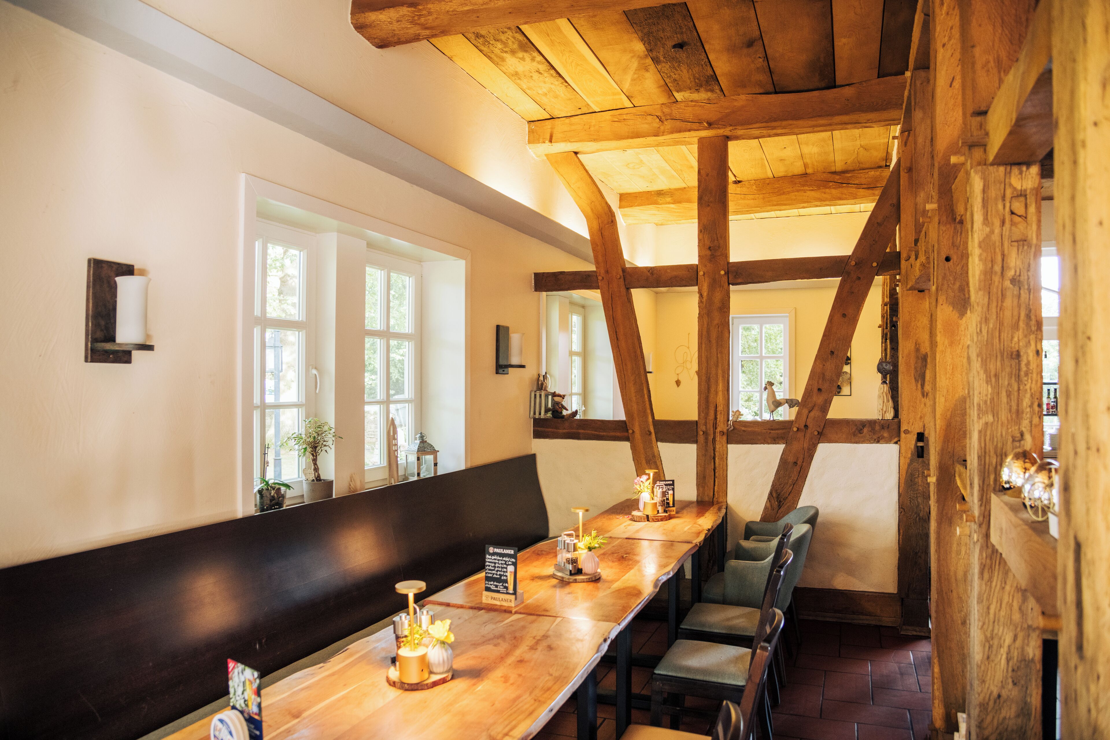 Een lange houten tafel met stoelen, een bank en een bord dat een restaurant aangeeft.
