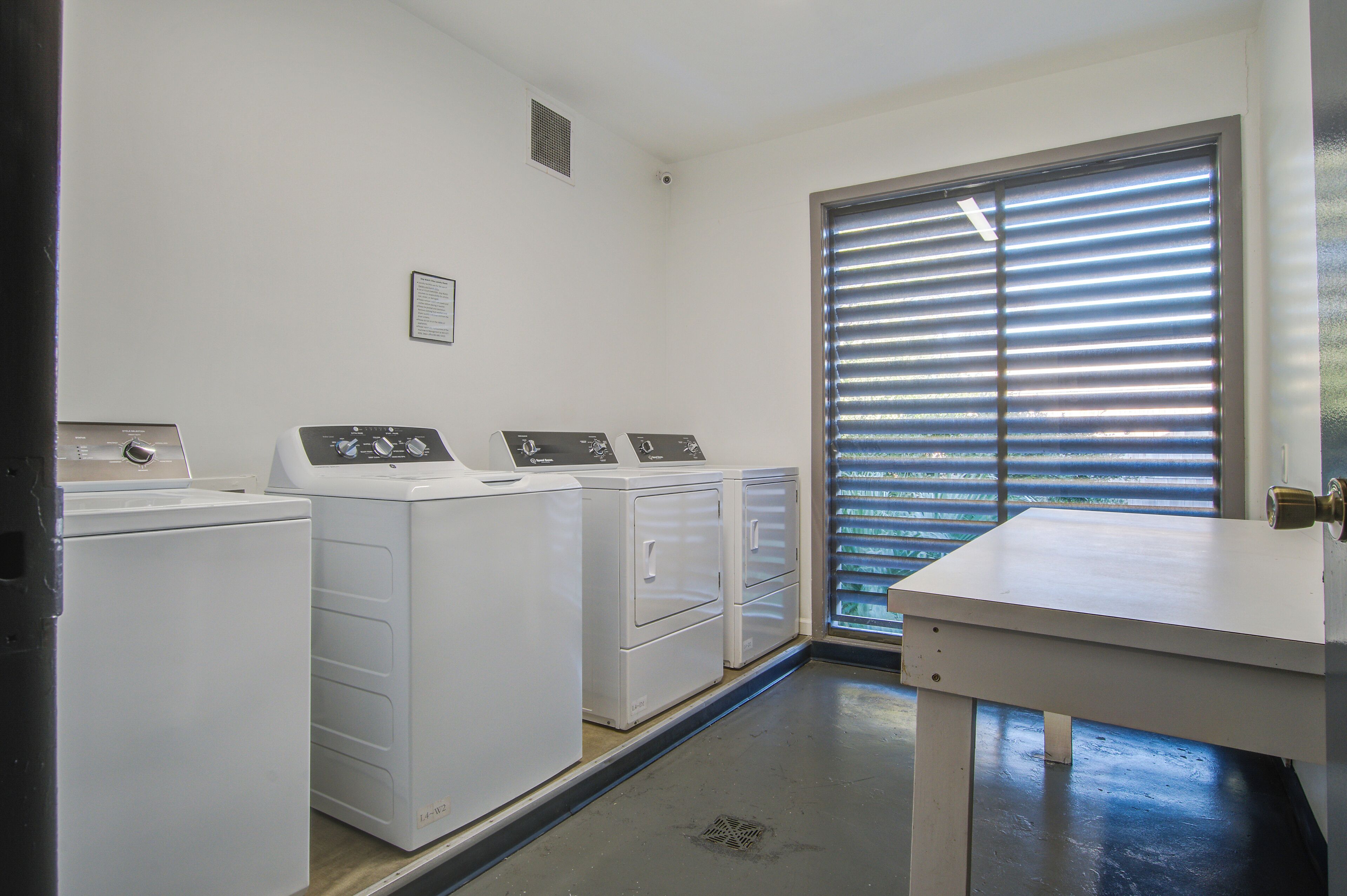 Un cuarto de lavandería con lavadora, secadora y mesa para doblar ropa.