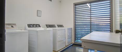 Un cuarto de lavandería con lavadora, secadora y mesa para doblar ropa.