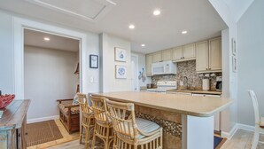 A kitchen with a large island, wooden chairs, and a microwave. - Three Oceanfront Private Balconies with Panoramic View, Dolphins & Calm Breezes! (Johns Island)