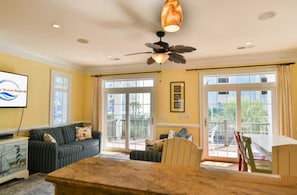 A living room with a sofa, a coffee table, a ceiling fan, and a large window.