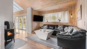 A modern living room with a black leather sofa, a white coffee table, a fireplace, and a TV mounted on the wall. - Nice home in Nørre Nebel with sauna (Nørre Nebel)