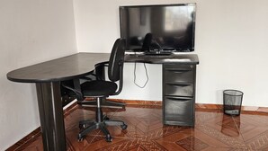 Ein kleiner Arbeitsraum mit Schreibtisch, Stuhl und Fernseher.
