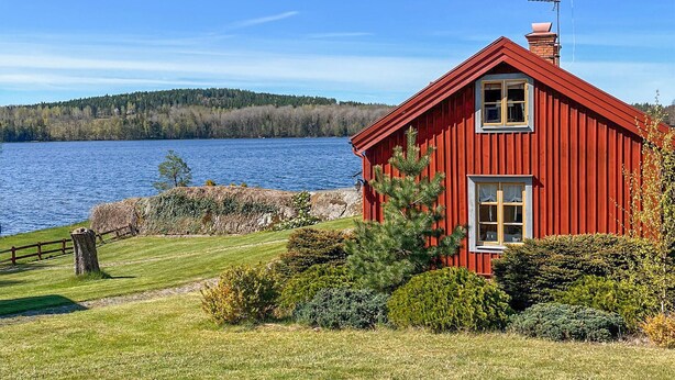 Una casa de madera roja con chimenea, una ventana y un pequeño porche.