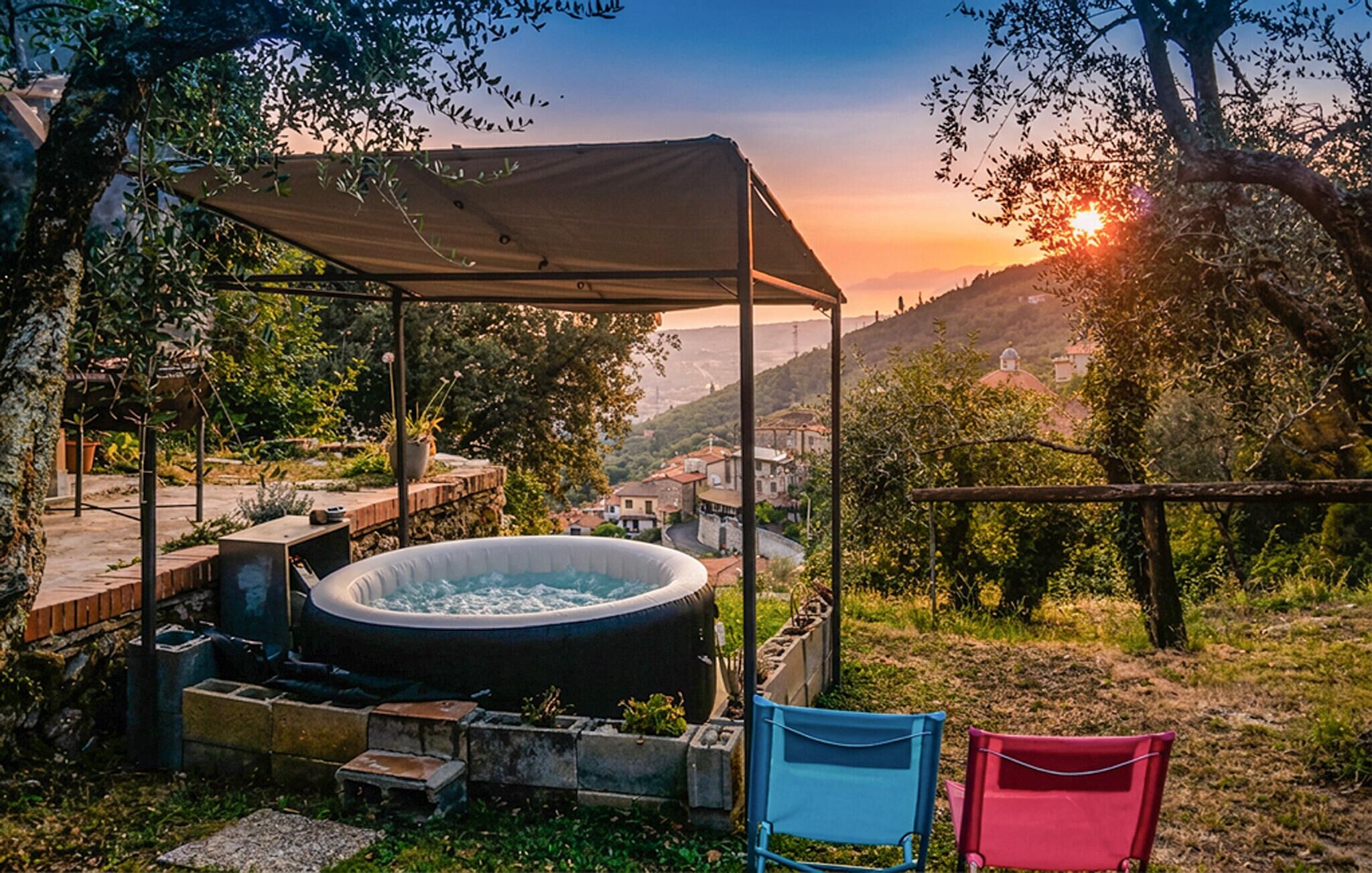 A hot tub under a canopy with a view of a hillside village.