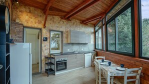 Une cuisine rustique avec des poutres en bois, un mur en pierre et une vue sur la verdure à l’extérieur.
