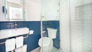 A bathroom with a white sink, a glass-enclosed shower, and a white toilet. - Private Cottage at Marina Bay (Waterford)