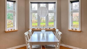 A dining area with a table and chairs, large windows with a view of greenery, and a hanging light fixture. - 3 bedroom cozy home in Havndal (Havndal)