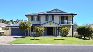 A two-story house with a front porch, a garage, and a well-maintained lawn. - Jaspa - River Views. (South West Rocks)