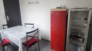 A room with a table covered in a lace tablecloth, two chairs, a red refrigerator, and a glass-fronted cabinet with various items. - 3 bedrooms with garage - Read the description  (Centro Juiz de Fora)