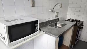 A compact kitchen with a white microwave, stainless steel sink, and gas stove. - 3 bedrooms with garage - Read the description  (Centro Juiz de Fora)