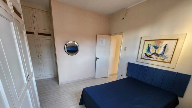 A bedroom with a bed, a wardrobe, a door, and a painting on the wall. - 3 bedrooms with garage - Read the description  (Centro Juiz de Fora)