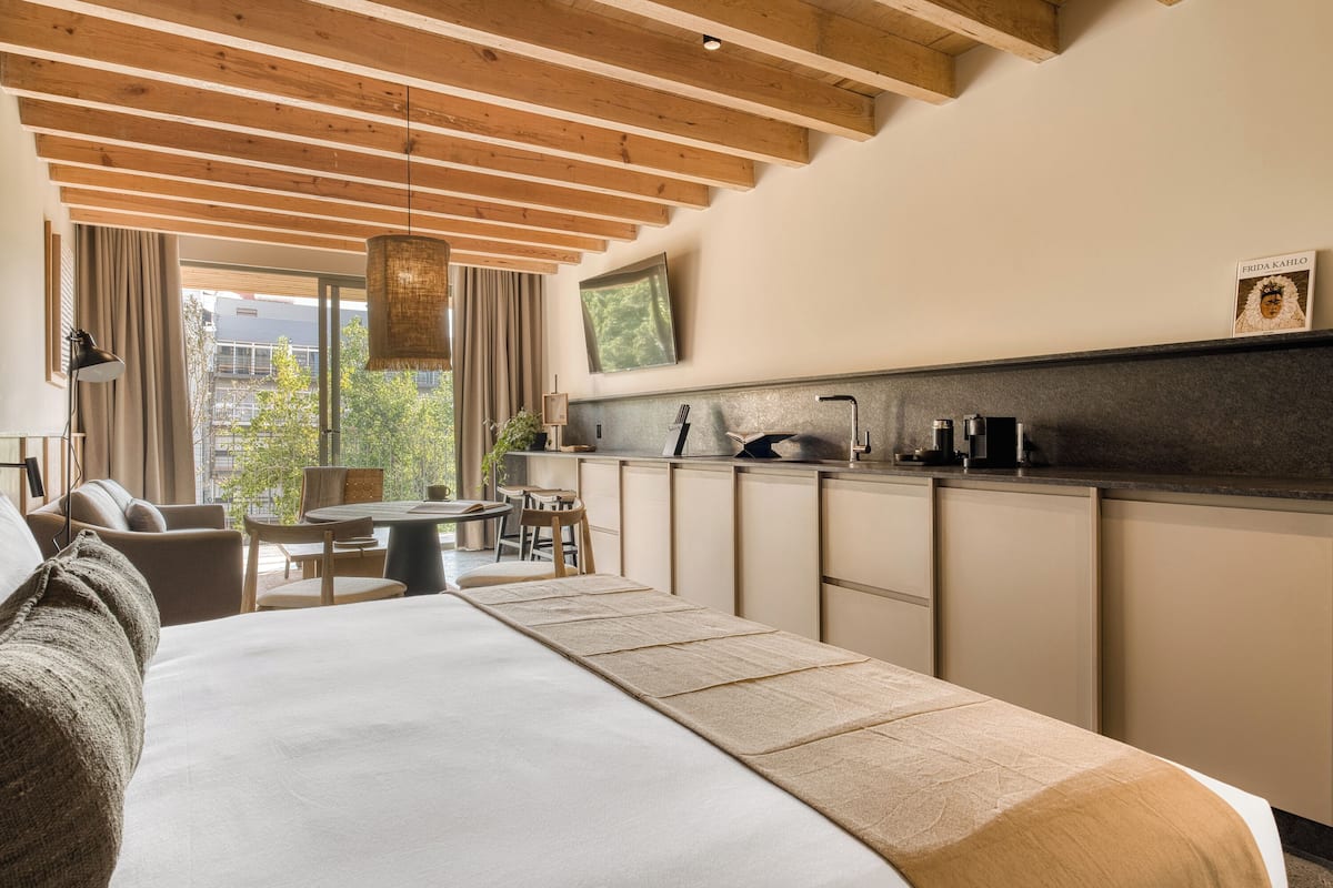 Una habitación de hotel moderna con una cama grande, un rincón de comedor y una kitchenette.