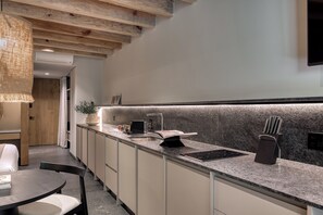 A modern kitchen with a granite countertop, built-in sink, and a hanging light fixture.