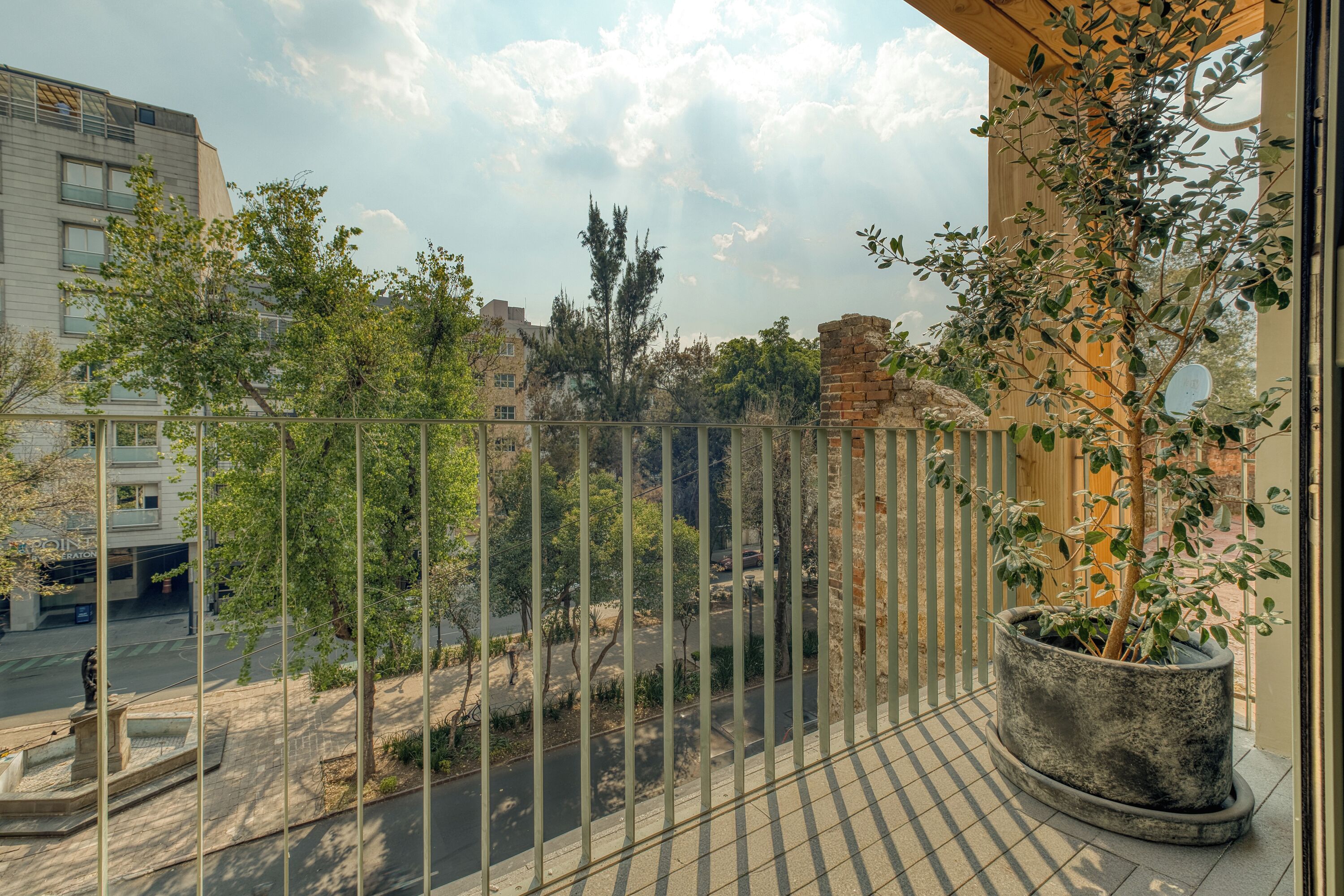 Ein Balkon mit Blick auf eine Straße, einem Blumentopf und einem Gebäude im Hintergrund.