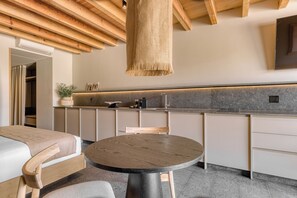 A modern kitchen with a round wooden table, a hanging light fixture, and a built-in oven.