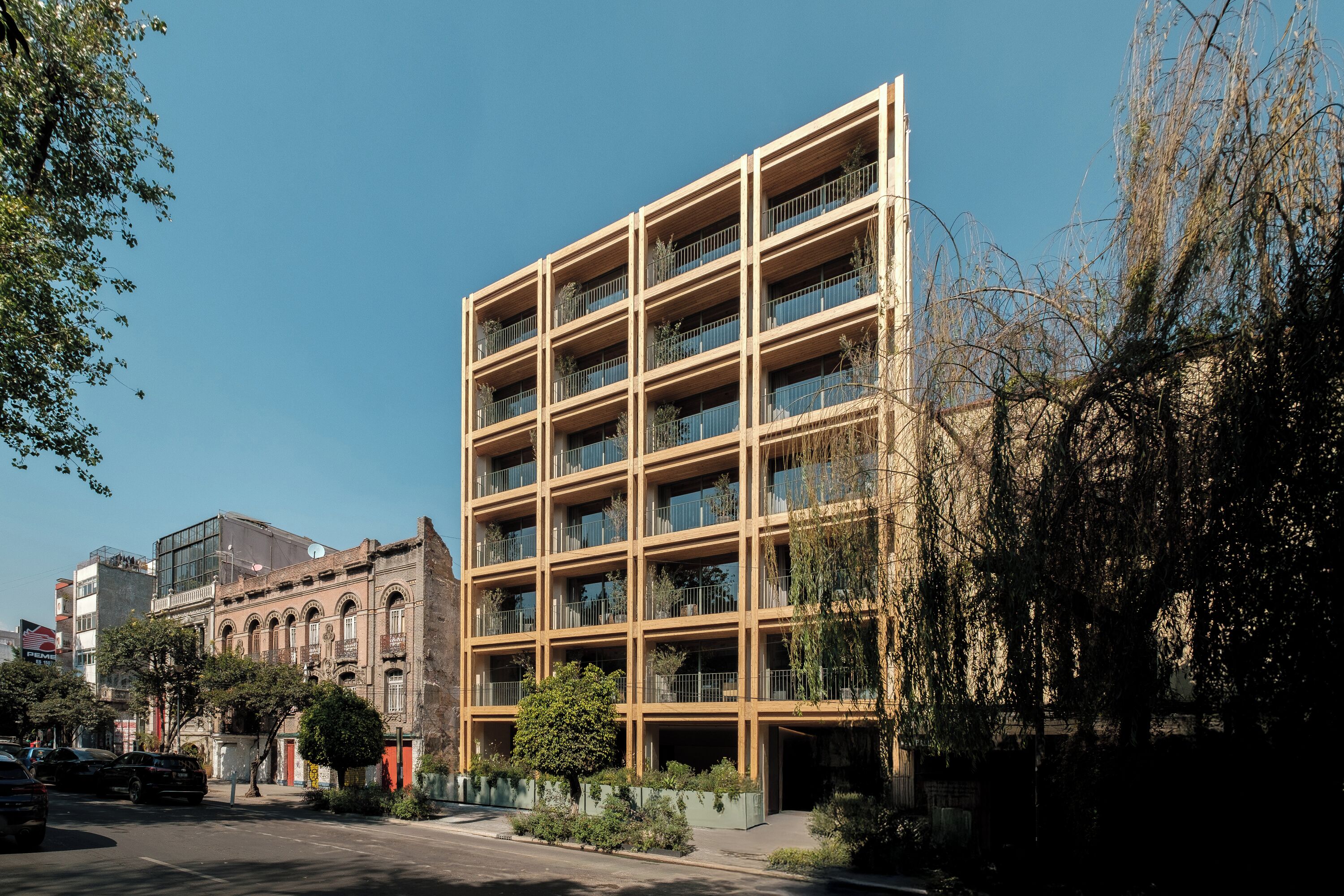 Un edificio de varios pisos con fachada enrejada, balcones y una combinación de elementos arquitectónicos modernos y tradicionales.