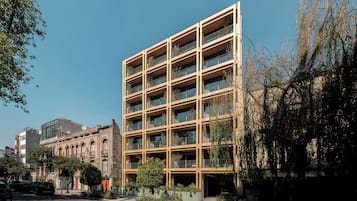 Un edificio de varios pisos con fachada enrejada, balcones y una combinación de elementos arquitectónicos modernos y tradicionales.