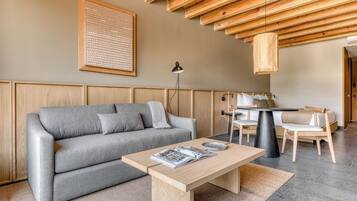 Ein modernes Wohnzimmer mit einem grauen Sofa, einem Holztisch und einem Essbereich mit Tisch und Stühlen.