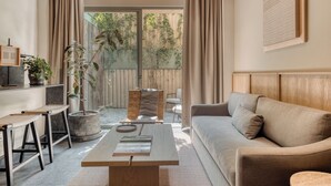 A modern living room with a sofa, coffee table, and bar stools. There is a large window with curtains, a potted plant, and a view of a wooden fence. - ONTO Alvaro Obregon Mexico City (Mexico City)