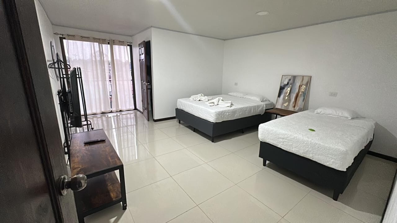 A hotel room with two beds, a desk, a chair, and a door.
