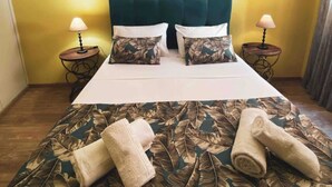 A hotel room with a bed, two nightstands, a painting on the wall, and a large window with curtains.