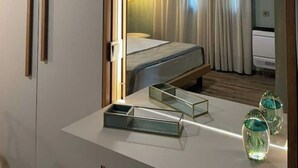 A hotel room with a bed, a desk, and a mirror reflecting the room. - Anamar Apt (Alepou)