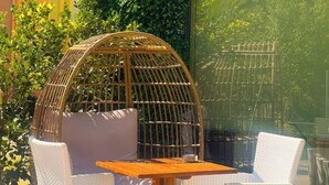 A patio with wicker furniture and a glass door. - Anamar Apt (Alepou)