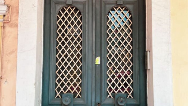 A double door with a lattice design and two circular motifs on the upper panels. - Downtown Oasis (Kerkira)