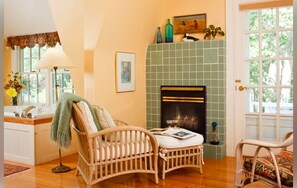 A cozy room with a fireplace, wicker furniture, and a view of the outdoors.
