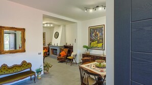 A dining area with a wooden table, chairs, and a bench. There is a fireplace with a clock on the wall. - Villa Scini by Rentbeat (Roma)