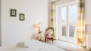 A bedroom with a bed, a chair, a table with a lamp, and two framed pictures on the wall. - Villa Scini by Rentbeat (Roma)