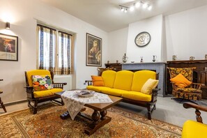 A living room with a yellow sofa, patterned rug, and a fireplace. - Villa Scini by Rentbeat (Roma)