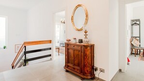 A staircase with a wooden handrail, a wooden cabinet with a mirror, and a hanging light fixture. - Villa Scini by Rentbeat (Roma)