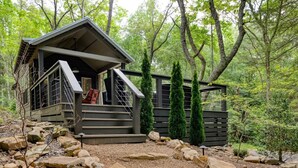 A cabin with a wooden exterior, a porch, and a staircase leading to the entrance. - Creekside Tiny house in fantastic Monteagle! Quick hike to waterfall!  (Monteagle)