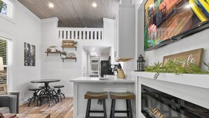 A modern kitchen with a central island, bar stools, and a fireplace. - Creekside Tiny house in fantastic Monteagle! Quick hike to waterfall!  (Monteagle)