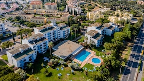 A residential area with apartment buildings, a swimming pool, and a road.